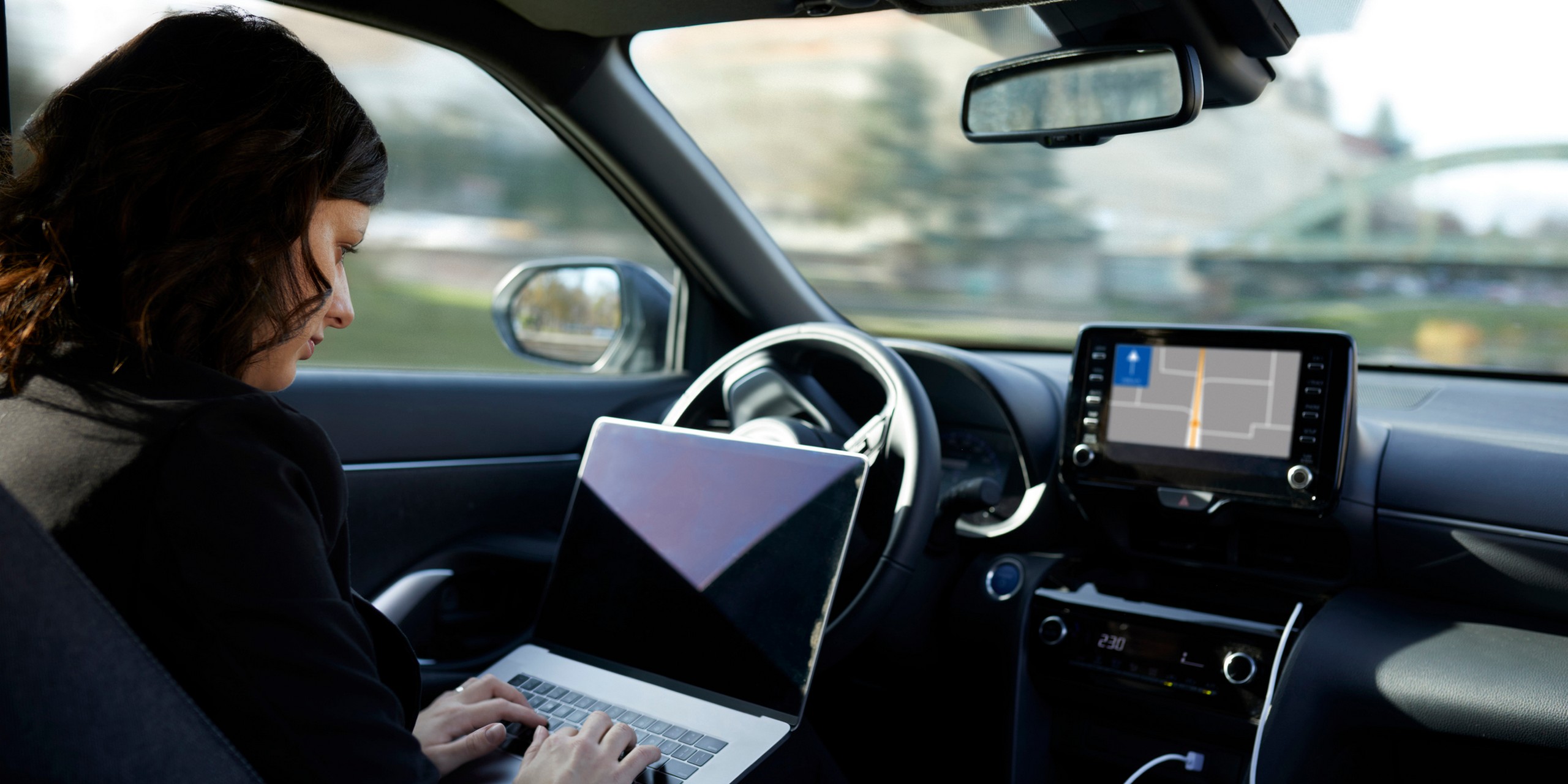 Businesswoman with laptop working in driverless car