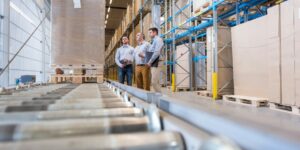 Three men talking in factory warehouse