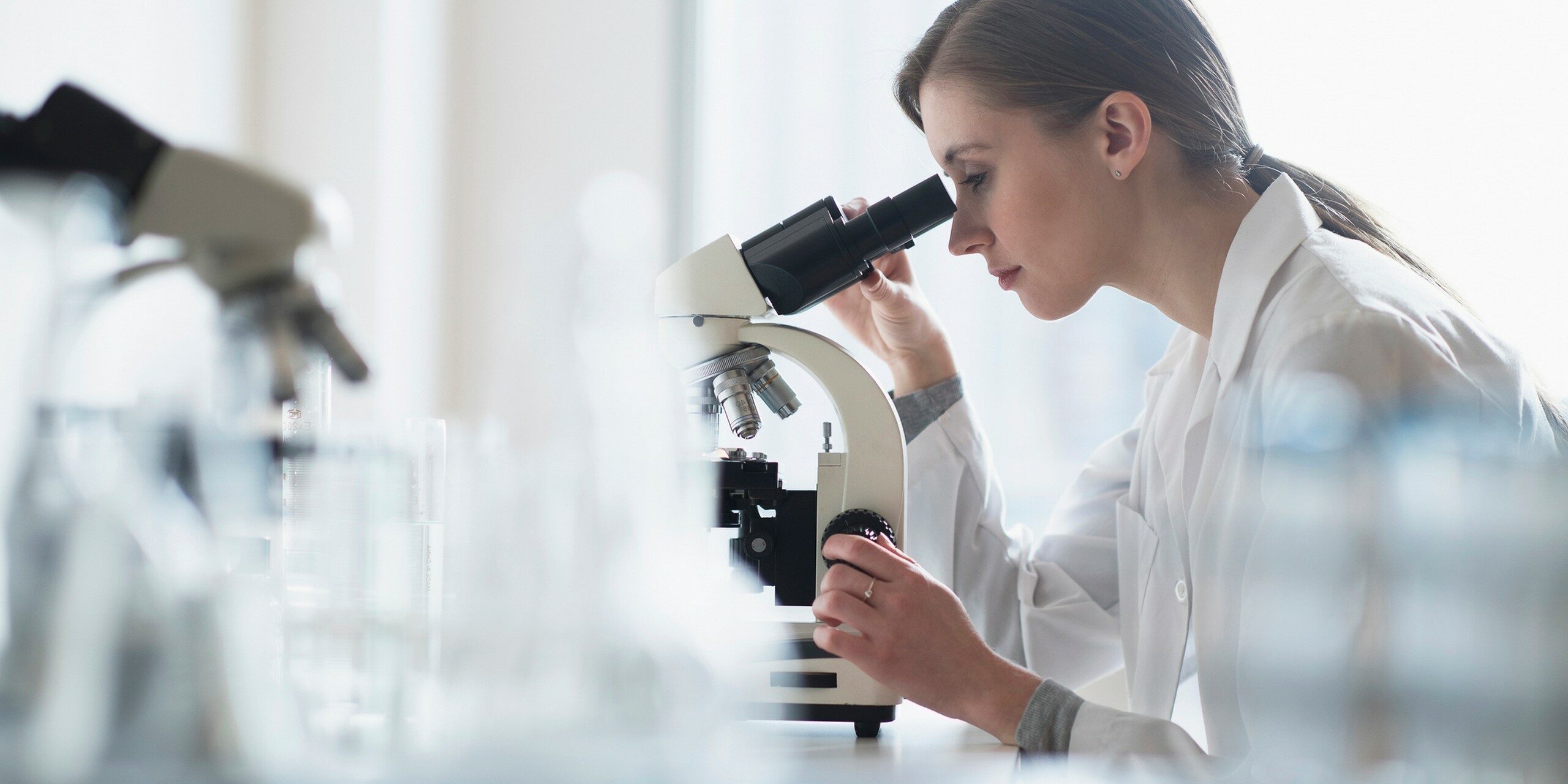 USA, New Jersey, Female lab technician analyzing sample through microscope