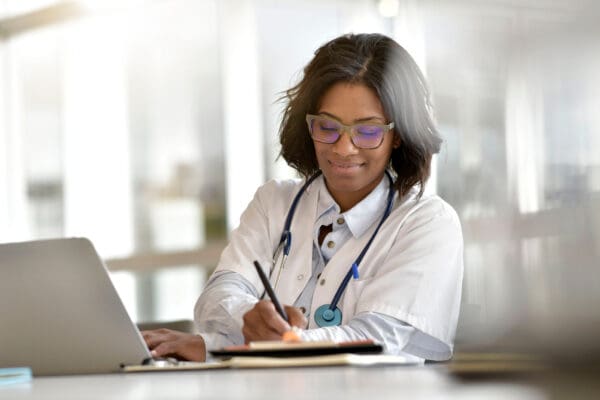 Woman doctor working in office with laptop computer, Eraneos Switzerland