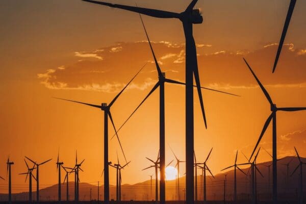 the sun is setting behind a group of windmills